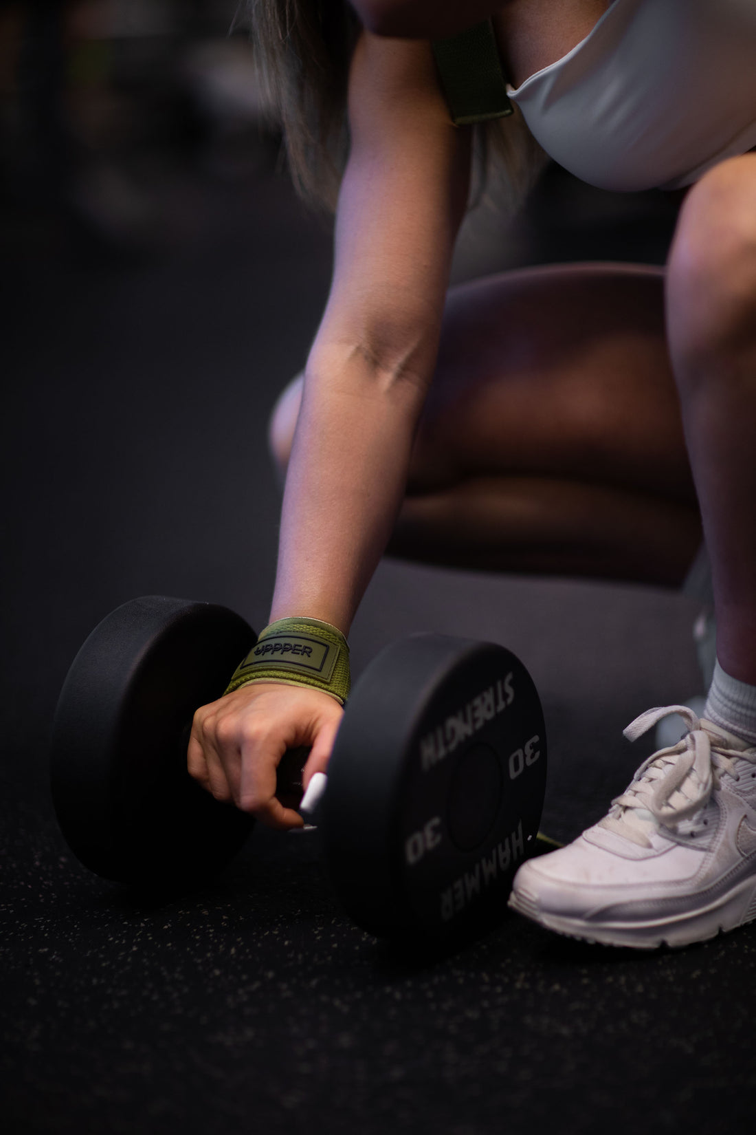 woman gripping dumbbell with uppper lifting straps