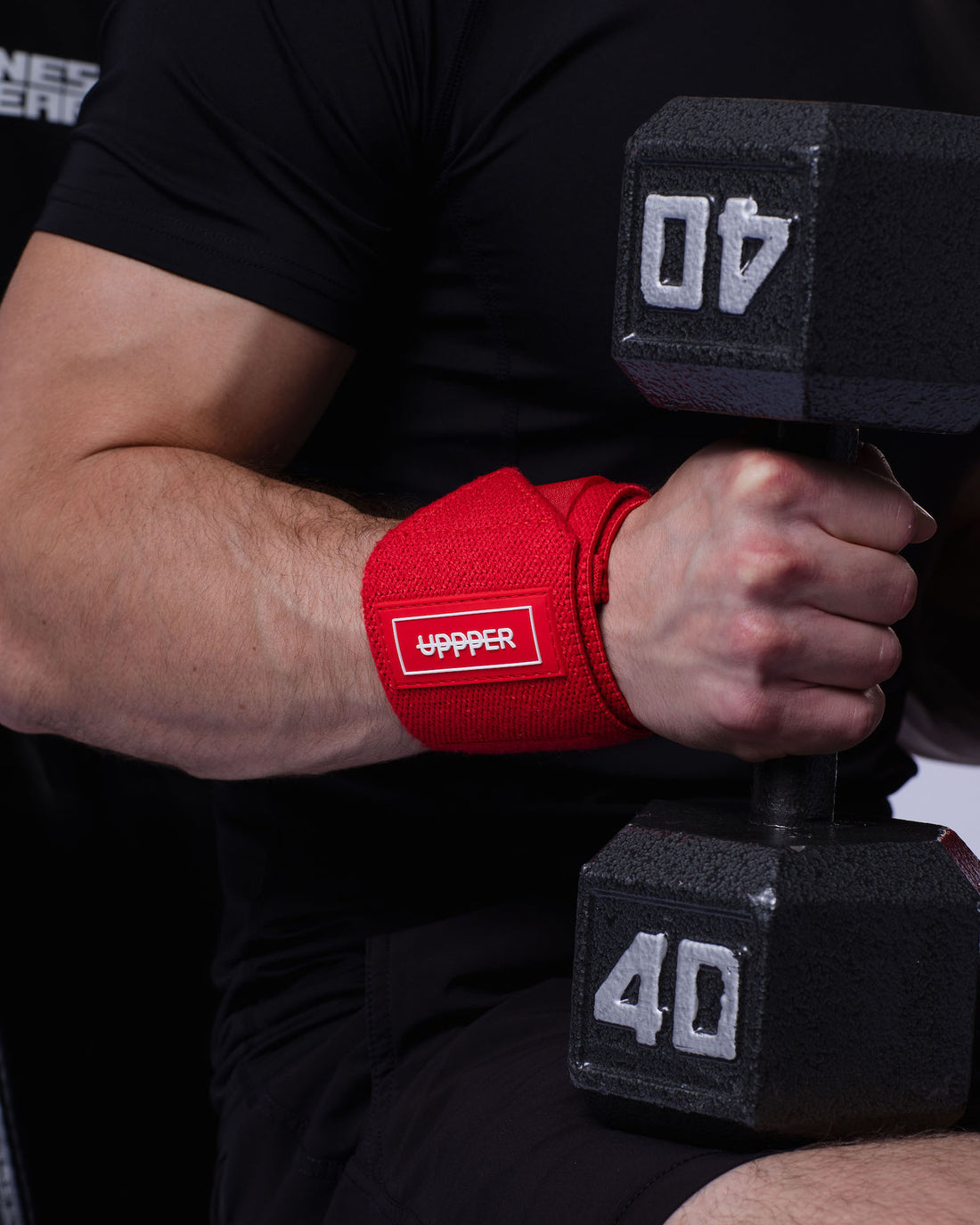 man gripping dummbell using uppper wrist wraps red